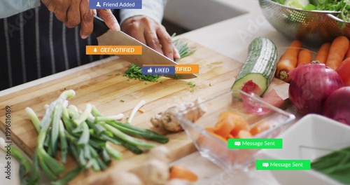 Chopping senior Indian cook prepping herbs in kitchen with knife and board, social labels, apron