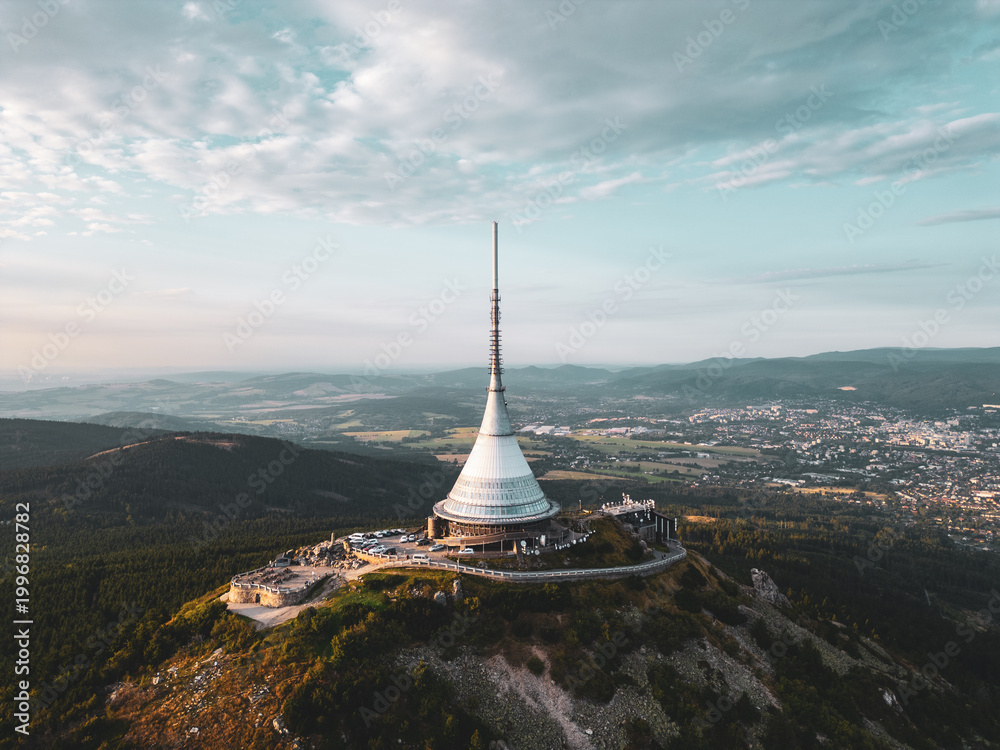 Naklejka premium Jested Mountain Hotel, nestled in Liberec, showcases modern architecture against a picturesque sunset. The scene captures the hotel's unique silhouette with surrounding landscapes.
