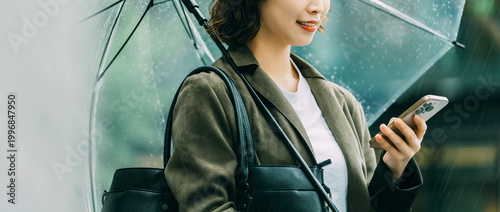 Quadro su tela 雨の日に傘を差しながらスマートフォンを使う日本人女性・ビジネスウーマンのビジネスイメージ（LP・バナー向け）, Japanese Businesswoman U