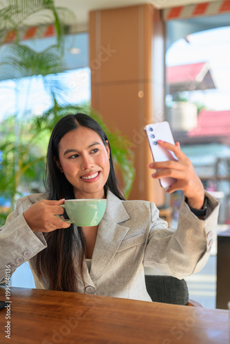 An authentic Asian woman from Thai Isan taking a selfie in a professional cafe.