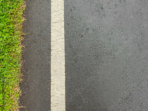 Top Down Aerial View of Wet Black Asphalt Road Surface with White Solid Lane Marker Dividing Line and Fresh Green Grass Edge after Rain Texture Background Rural Highway Path Travel Infrastructure