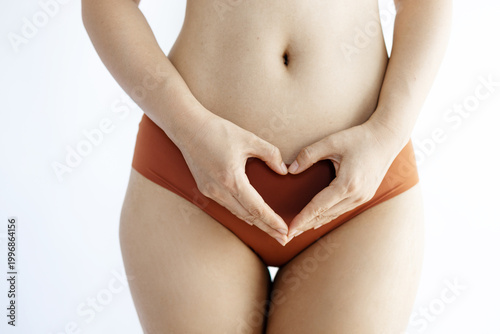 Foto Close-Up of a Woman's Hands Making a Heart Shape Over Her Abdomen in Brown Under