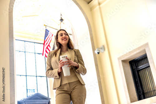 Businesswoman standing in manhattan lobby building holding travel tumbler