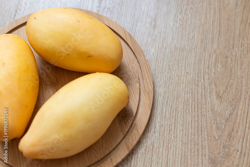 Fresh yellow picked mangoes displayed on wooden board
