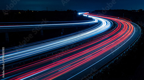 Tableau sur toile Winding highway at night with dramatic car light trails, conveying speed and modern transportation against a dark