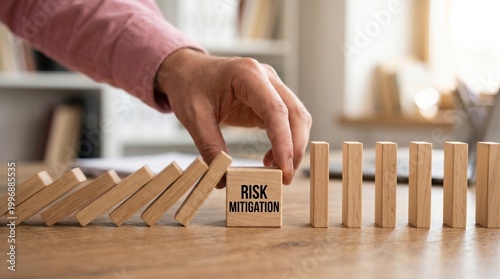Risk Mitigation Concept: A human hand strategically prevents a chain reaction of falling dominoes, symbolizing effective risk management and the act of mitigating potential threats.