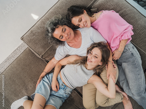 Mother cuddling with daughters on couch showing family affection