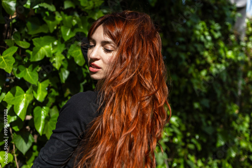 Portrait of a red-haired woman on a green background.