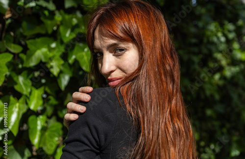 Portrait of a red-haired woman on a green background.
