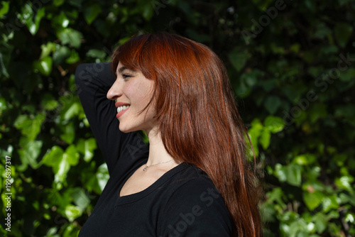 Portrait of a smiling redheaded woman against a green background.