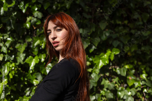 Portrait of a red-haired woman on a green background.