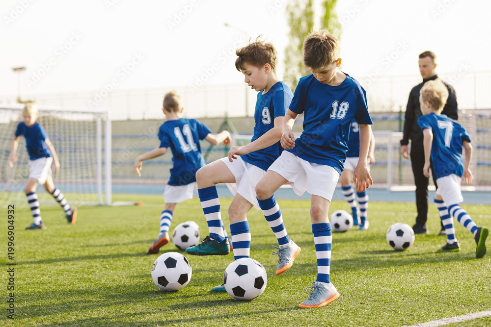 Obraz premium Soccer Academy Training. Football soccer training for kids. Children's football training session. Kids running and kicking soccer balls. Young boys are improving their soccer skills