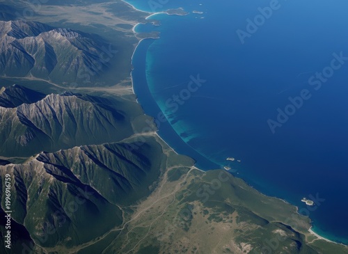 Aerial view of rugged mountain range meeting the deep blue ocean coastline