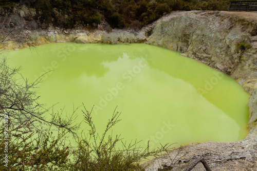 Vivid Green Geothermal Lake Surrounded Rocky Cliffs