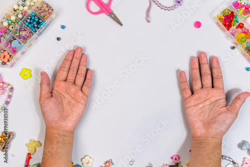 Child's hand with beads scissor string and bracelet, craft creativity concept background wallpaper