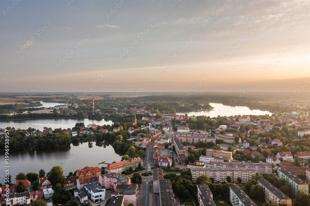Obraz premium Sunset aerial cityscape with rooftops, water and surrounding fields in Walcz, West Pomerania, Poland.