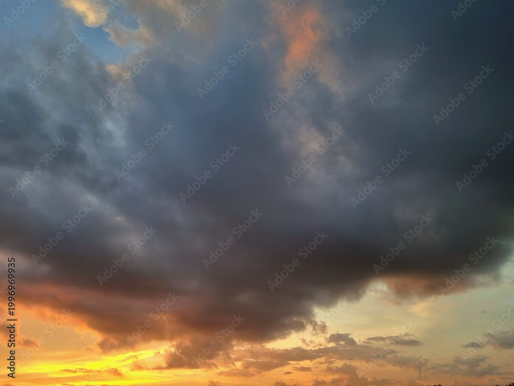 Obraz premium Dramatic sunset sky with vibrant orange and dark clouds at dusk