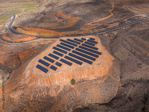 Фотография Grid-mounted photovoltaic solar panels arranged in parallel rows on an eroded re