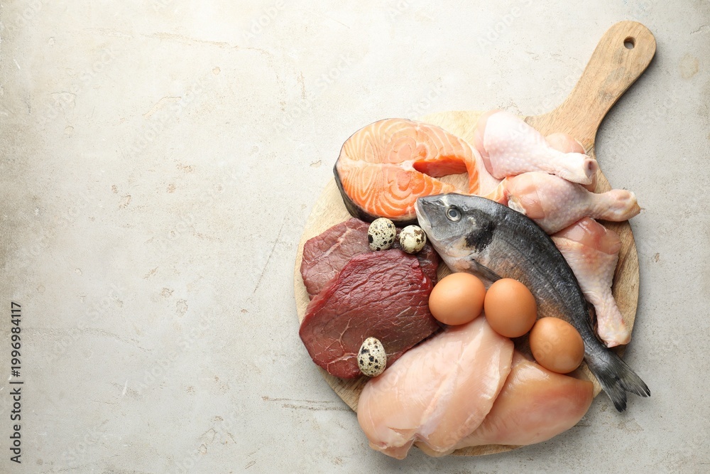 Naklejka premium Different types of fresh raw meat, fish and eggs on gray textured table, top view. Space for text