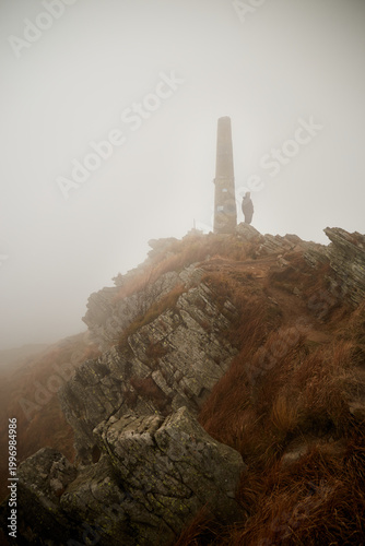 Fog envelops rocky terrain in a remote mountain landscape during a calm day in autumn. Autumn hiking in Carpathian Mountains, Ukraine