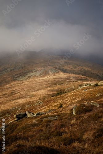 Scenic view from a mountain ridge showing clouds and distant hills during late afternoon. Autumn hiking in Carpathian Mountains, Ukraine