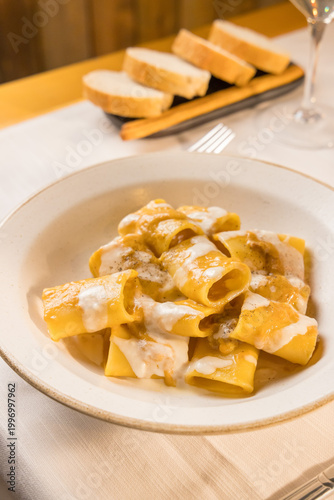 Fotografía Gourmet presentation of traditional Italian paccheri pasta coated in a rich, creamy cheese sauce