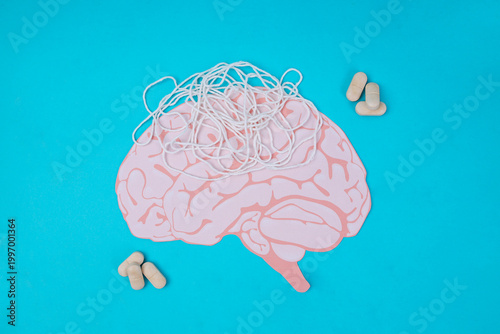Pink Paper Brain Cutout With Tangled White String And Pills On Blue Background