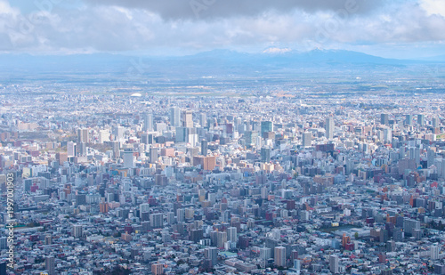 Foto 藻岩山展望台から見下ろす光が差し込む札幌の街並みと遠くの雪山 Sapporo cityscape bathed in sunlight and distant snow-capped mountains viewed from Mt