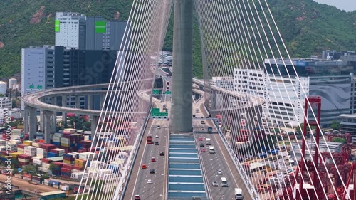 A unique view of traffic on a large suspension bridge. Revealing panoramic view of Hong Kong's container port and its city skyline