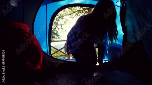 Young couple holding hands entering camping tent. Happy couple of campers entering their blue tent holding hands after a day of hiking in nature