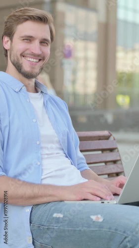Man with Laptop Smiling at Camera while Sitting Outdoor on Bench, Vertical Video