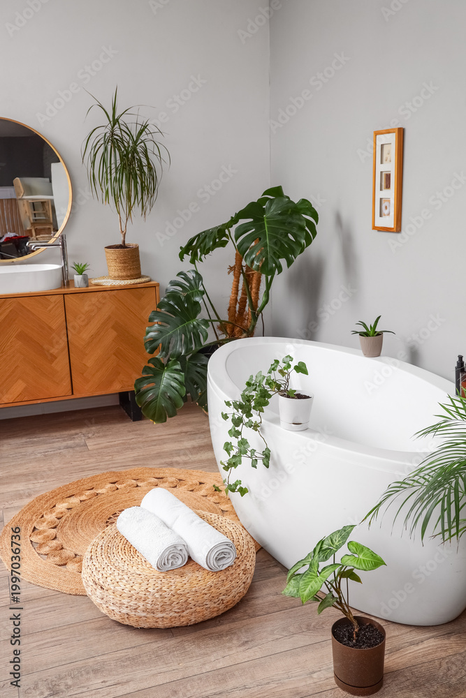 Fototapeta premium Interior of bathroom with green plants, sink and bathtub