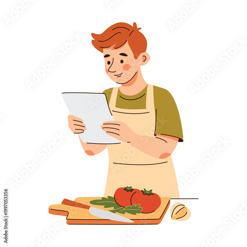 Young boy in apron holding and reading a recipe paper or list in the kitchen