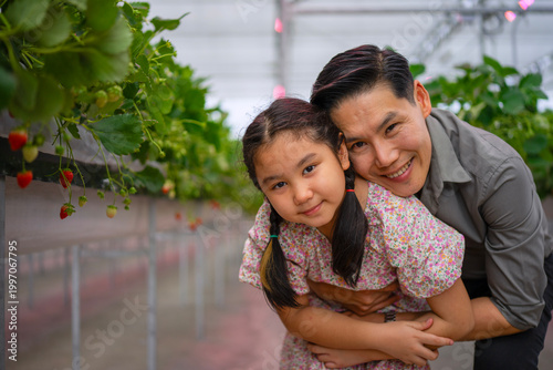 Father and daughter are travel at strawberry green house.