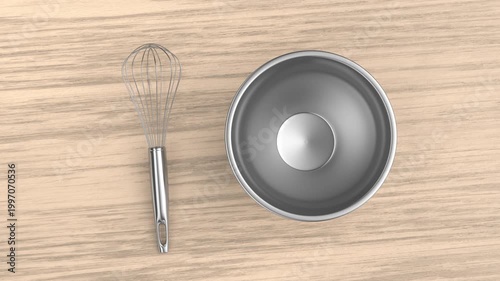 Balloon whisk and empty metal bowl on a wooden table
