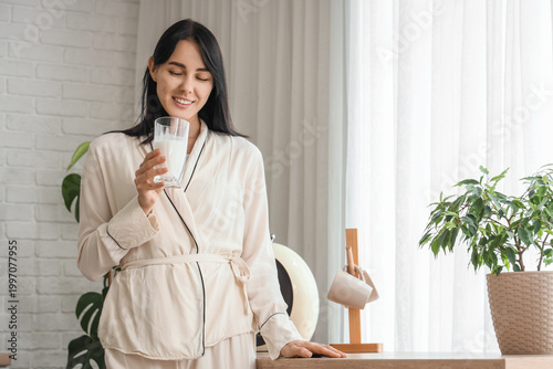 Beautiful woman with glass of milk in kitchen
