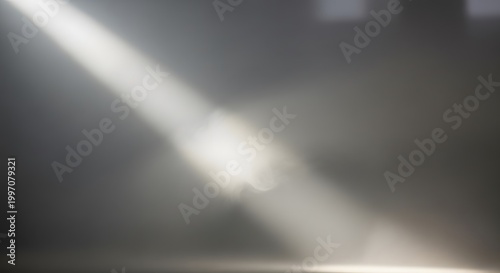 Bright diagonal light beam shining through a dark grey room