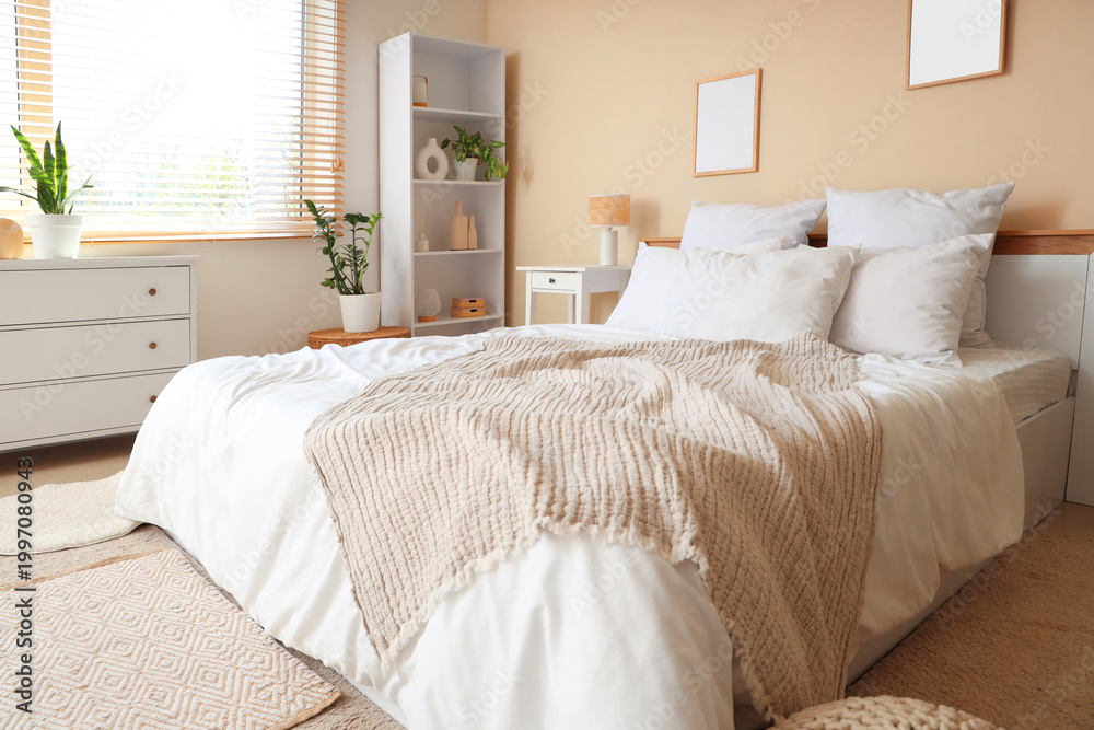 Fototapeta premium Interior of light bedroom with cozy bed, houseplants and bedside table