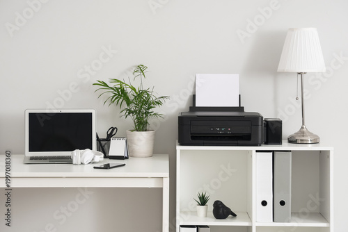 Stylish workplace with modern printer and laptop in light home office