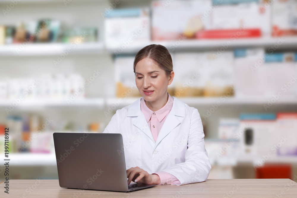 Fototapeta premium Pharmacist using laptop at table in drugstore