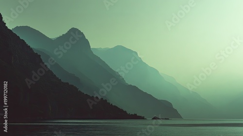 Mountain ridges receding into mist over a calm coastal sea, soft hazy sky and layered silhouettes conveying tranquil, minimal landscape and peaceful morning atmosphere