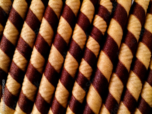 Tightly packed cylindrical wafer roll cookies display a spiral pattern of alternating light tan and dark chocolate brown stripes. 