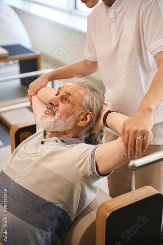 Elderly man receiving therapy support indoors, peaceful setting