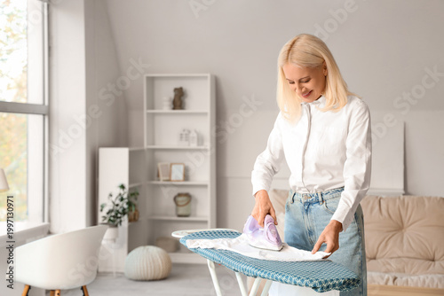 Happy mature woman ironing ...