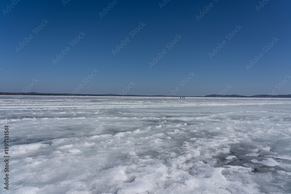 Obraz premium A Vast Frozen Landscape Under Clear Skies: The Beauty of Ice and Blue in a Winter Wonderland