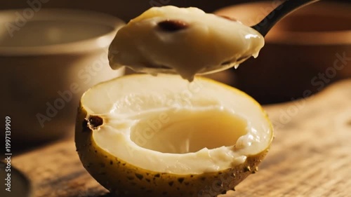 Creamy custard apple dessert on spoon, exotic cherimoya fruit pulp close up, tropical soursop yogurt snack on wooden table