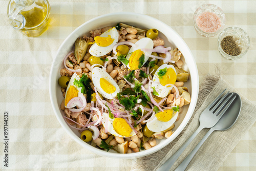 Cannellini Bean Salad with Tuna and Eggs on Checkered Tablecloth with Olive Oil and Cutlery
