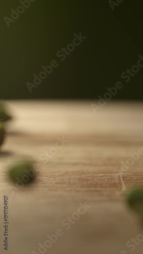 Slow motion green pistachios falling on wooden table