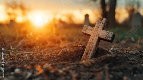 A weathered wooden cross partially emerges from the soft earth in a serene graveyard, illuminated by the warm glow of a beautiful sunset.