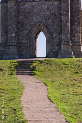 Foto Ancient St Michaels Tower on Glastonbury Tor with Bright Sun Flare and Clear Sky